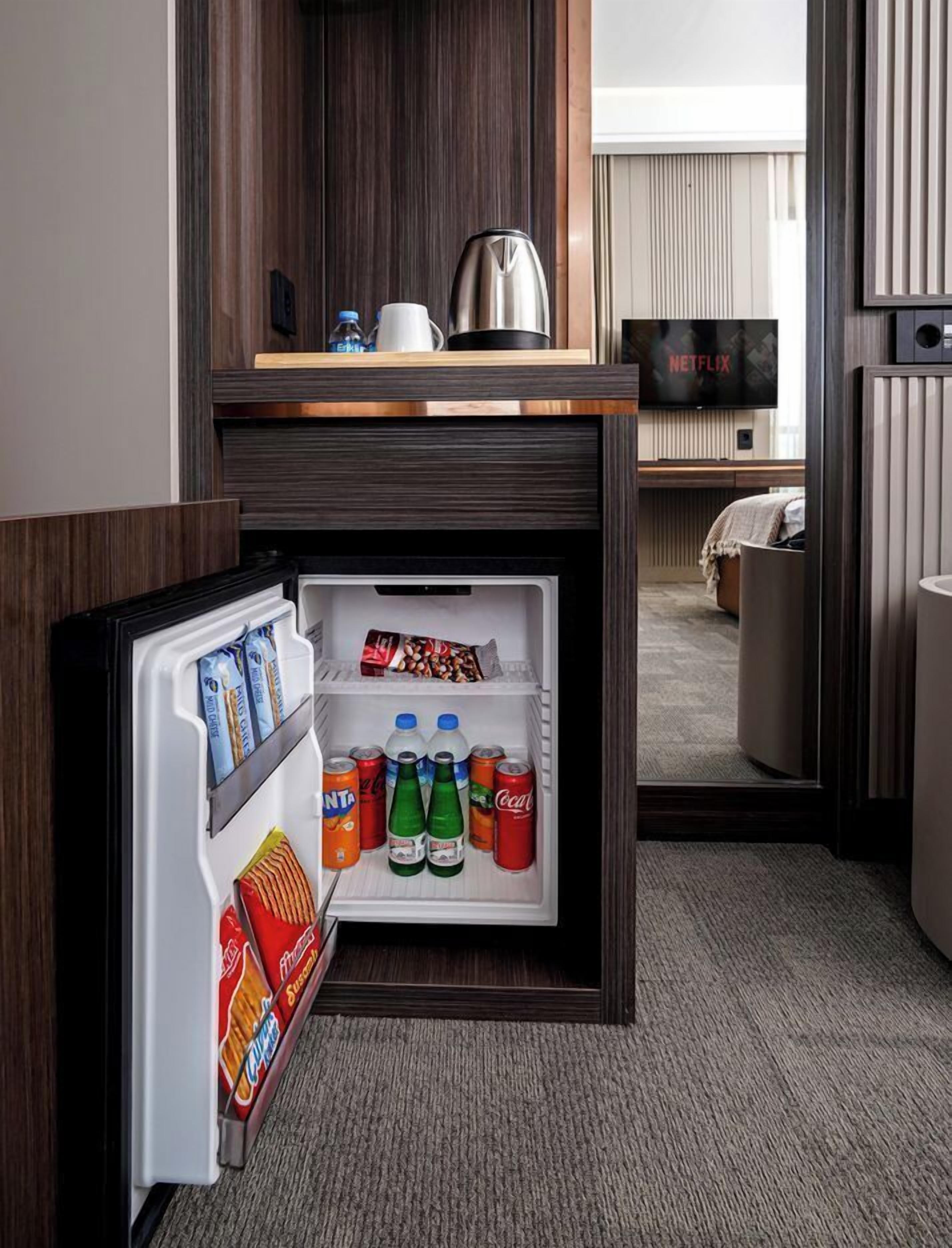 A compact kitchenette with a built-in refrigerator containing snacks and beverages.
