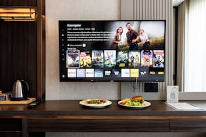 A flat-screen TV mounted on a wall displaying a movie selection interface with various streaming service logos. - Byon Hotel Şile (Sile)