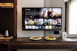 Un televisor de pantalla plana montado en la pared mostrando una interfaz de selección de películas con varios logotipos de servicios de streaming.