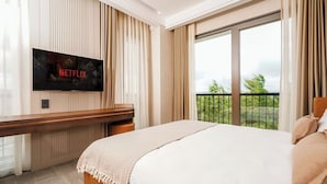 A hotel room with a bed, a TV mounted on the wall, a desk, and a balcony with a view. - Byon Hotel Şile (Sile)