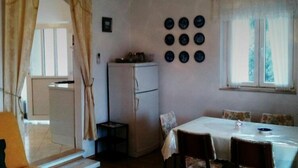 Una habitación compacta con una mesa de comedor, sillas, un refrigerador y un reloj de pared.