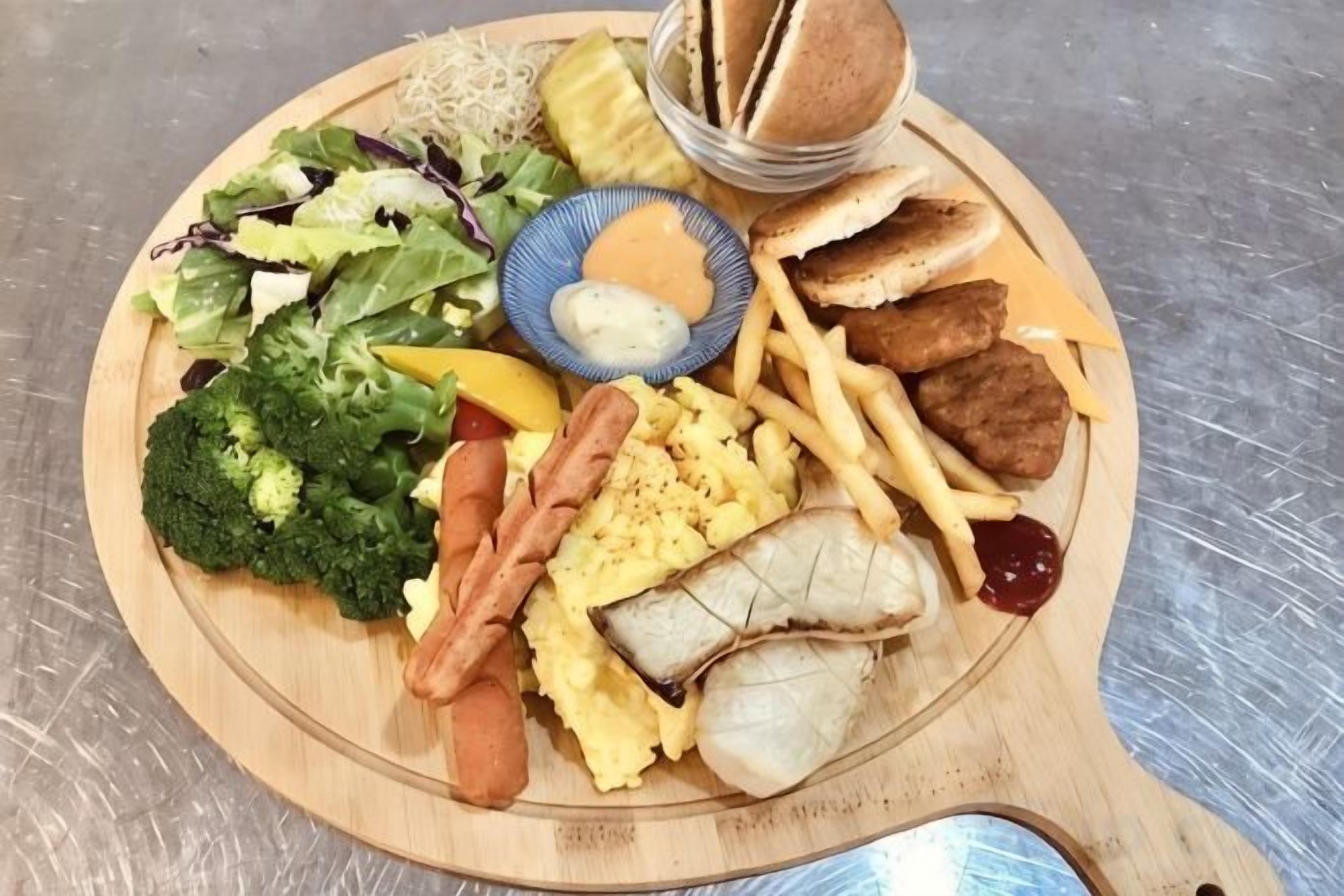 Una tabla de madera con diversos alimentos como pan, salchichas y verduras.