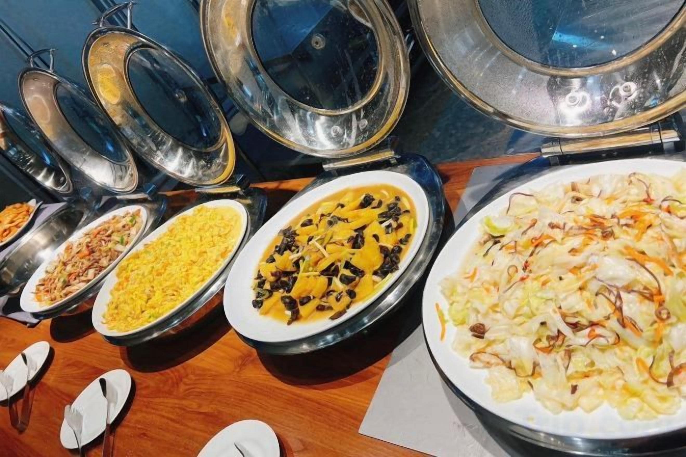 A buffet with various dishes in bowls and plates, including salads and rice dishes.