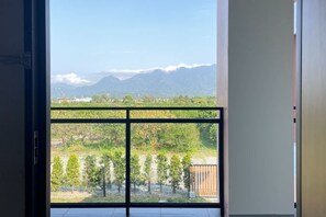 Une pièce dotée d’une grande fenêtre donnant sur un vignoble et des montagnes lointaines.