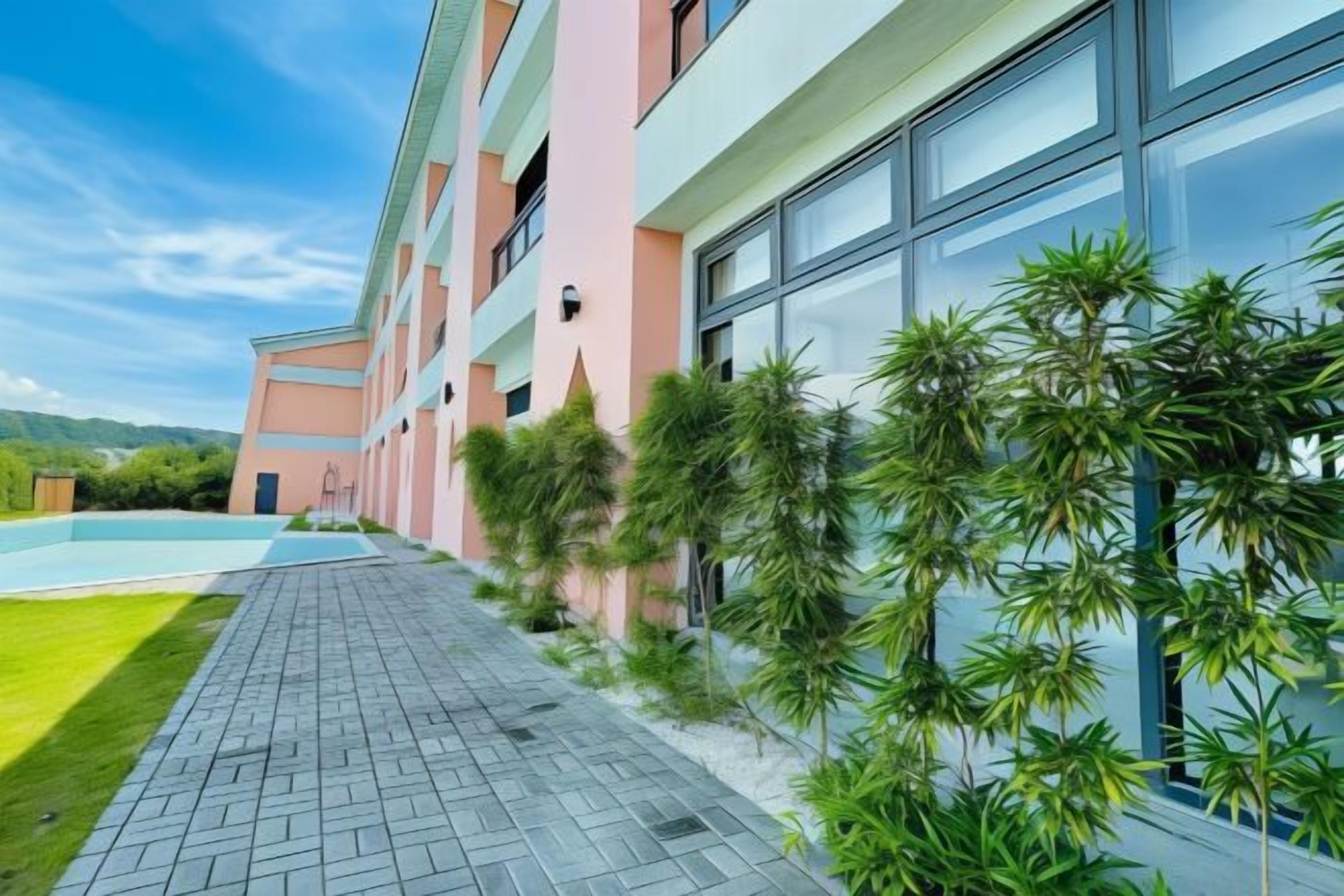 Un hotel con piscina, un paseo empedrado y una fila de ventanas.