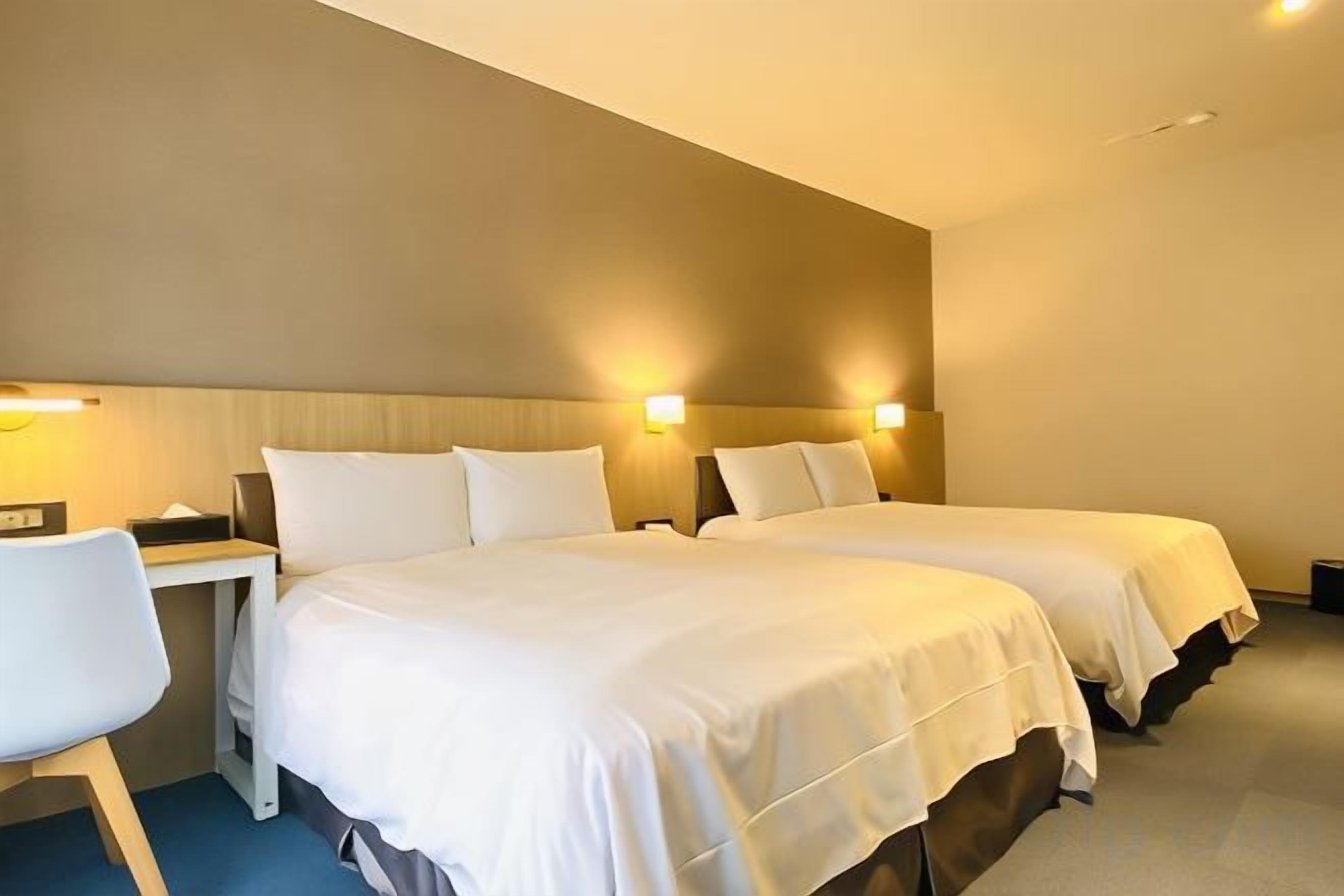 Una habitación de hotel con dos camas, un escritorio y una silla.