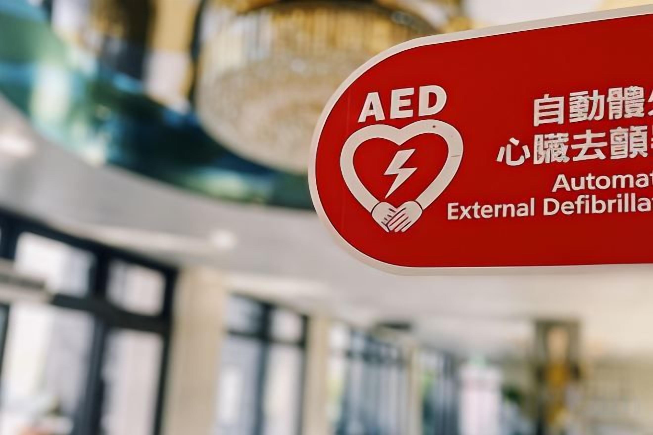 A red AED emergency sign with text in English and another language.