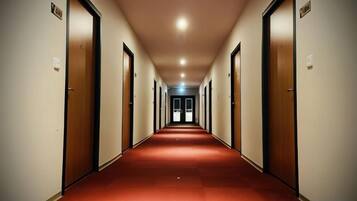 A long, narrow hallway with doors on both sides, leading to a bright end.
