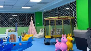 A play area with a blue boat, a pink and yellow toy horse, and a trampoline.