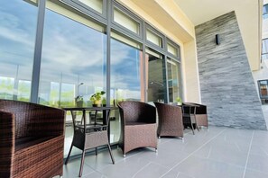 A modern outdoor seating area with wicker furniture and a glass table, overlooking a cityscape. - Mizuho Hotel (Hualien)