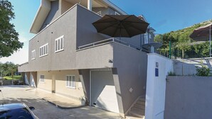 Un edificio de dos pisos con techo plano, un espacio al aire libre cubierto con una sombrilla y una puerta de garaje.