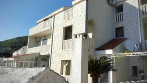 A multi-story building with balconies, a satellite dish, and a view of a hillside. - Apartments Villa Angela - Studio Apartment with Terrace and Sea View (Angela) (Baška Voda)