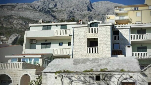 A multi-story building with balconies and a mountainous backdrop. - Apartments Villa Angela - Studio Apartment with Terrace and Sea View (Angela) (Baška Voda)
