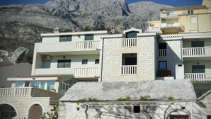 Un edificio de varios pisos con balcones y montañas al fondo.