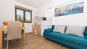 Eine moderne Wohnung mit Essbereich, Küche und einem blaugrünen Sofa.