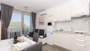 A compact kitchen with white cabinets, a microwave, and a small refrigerator.