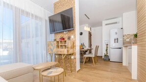 A modern living room with a sofa, a dining table, and a TV mounted on a wall. - Villa LA-Two Bedroom Apartment with Terrace (Drvenik Veliki)