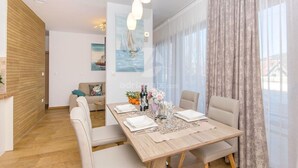 A dining area with a wooden table set for four, a sofa, and a painting on the wall. - Villa LA-Two Bedroom Apartment with Terrace (Drvenik Veliki)