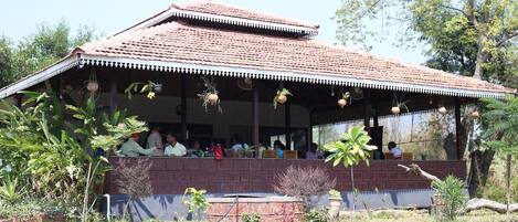 A building with a tiled roof and a covered porch with hanging planters.