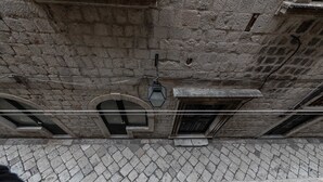A stone building with arched windows and a tiled ground.