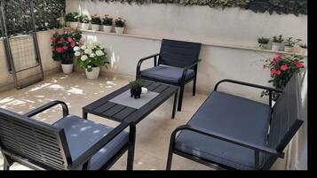 Un balcon doté d’un espace salon, comprenant deux chaises et une table, et agrémenté de plantes en pot.