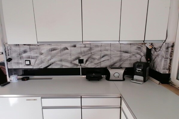 A kitchen with white cabinets, a black countertop, a coffee machine, and a microwave. - Villa Elit-Two Bedroom Apartment with Sea View Terrace ( A1) (Sumpetar)
