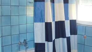 A bathroom with blue tiled walls, a white bathtub, and a checkered shower curtain. - Villa Elit-Two Bedroom Apartment with  Sea View Terrace ( A1) (Sumpetar)
