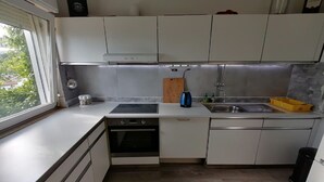 A compact kitchen with white cabinets, a built-in oven, a sink, and a window providing a view of greenery outside. - Villa Elit-Two Bedroom Apartment with  Sea View Terrace ( A1) (Sumpetar)