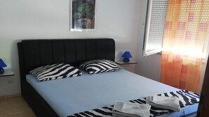 A bed with a zebra-patterned bedspread and pillows, a blue lamp on a bedside table, and a window with blinds. - Villa Elit-Two Bedroom Apartment with  Sea View Terrace ( A1) (Sumpetar)