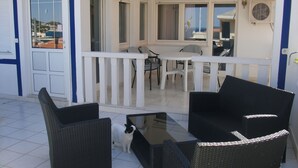 A balcony with a table and chairs, a white cat, and a view of the sea. - 2 bedroom apartment with terrace (Sumpetar)