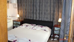 A hotel room with a bed, two bedside tables with lamps, a nightstand, a wall-mounted heater, and a bathroom with a sink and mirror. - 2 bedroom apartment with terrace (Sumpetar)