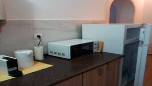 Una cucina con un forno a microonde, un tostapane, un rotolo di carta assorbente e una macchina da caffè sul piano di lavoro.