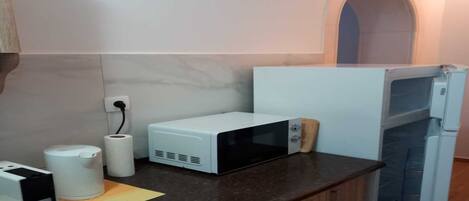 A kitchen with a microwave, a toaster, a roll of paper towels, and a coffee maker on the counter.
