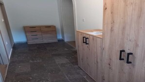 Una stanza con un armadio in legno, un piccolo mobiletto e un pavimento piastrellato.