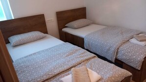 Due letti singoli con poggiatesta in legno, ognuno con una coperta a fantasia e cuscini.