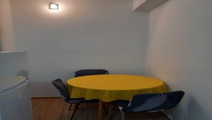 Una zona pranzo modesta con un tavolo giallo e quattro sedie.