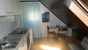 A compact kitchen with a sink, stove, and dining area with a table and chairs. - Villa Elit- Three Bedroom Apartment with Sea View Terrace (Penthouse) (Sumpetar)