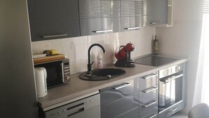A modern kitchen with a sink, a kettle, a red mixer, and a bottle of olive oil on the counter. - Apartments Kalajzic-  One Bedroom Apartment with Terrace(A3) (ST) (Pucisca)