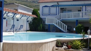 A swimming pool with lounge chairs, a staircase, and a building with a blue and white color scheme. - Villa Elit - Comfort Two Bedroom Apartment with Terrace ( A5) (Sumpetar)