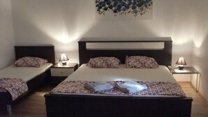 A hotel room with two single beds and one double bed. Each bed has a pillow and a small bedside table with a lamp. There is a wall art piece above the double bed. - Villa Elit - Comfort Two Bedroom Apartment with Terrace ( A5) (Sumpetar)