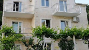 Un bâtiment à deux étages doté de balcons, d’une entrée centrale et d’une structure recouverte de plantes grimpantes à l’avant.