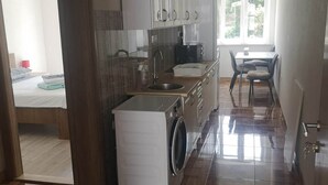 Une cuisine compacte équipée d’un lave-linge, d’un évier et d’un coin repas avec des chaises.
