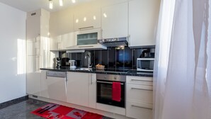 Een moderne keuken met witte kastjes, een zwart aanrecht, een inbouwoven en een magnetron.