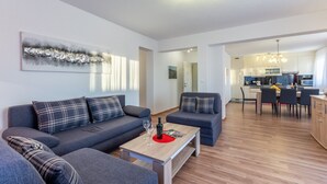 Een moderne woonkamer met een zithoek, een salontafel en een keuken op de achtergrond.
