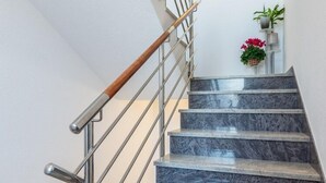 A staircase with a wooden handrail and metal balusters, leading to a landing with a potted plant. - Apartments Palma -Studio with Balcony  and Sea View( Mali ) (Stanici)