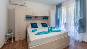 A bedroom with a bed, a wardrobe, a small table, and an air conditioning unit. - Apartments Palma -Studio with Balcony  and Sea View( Mali ) (Stanici)