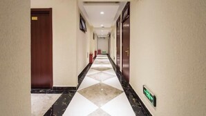 Een hotelgang met een receptiebalie, een ontvangstruimte en een bord dat de lift aangeeft.