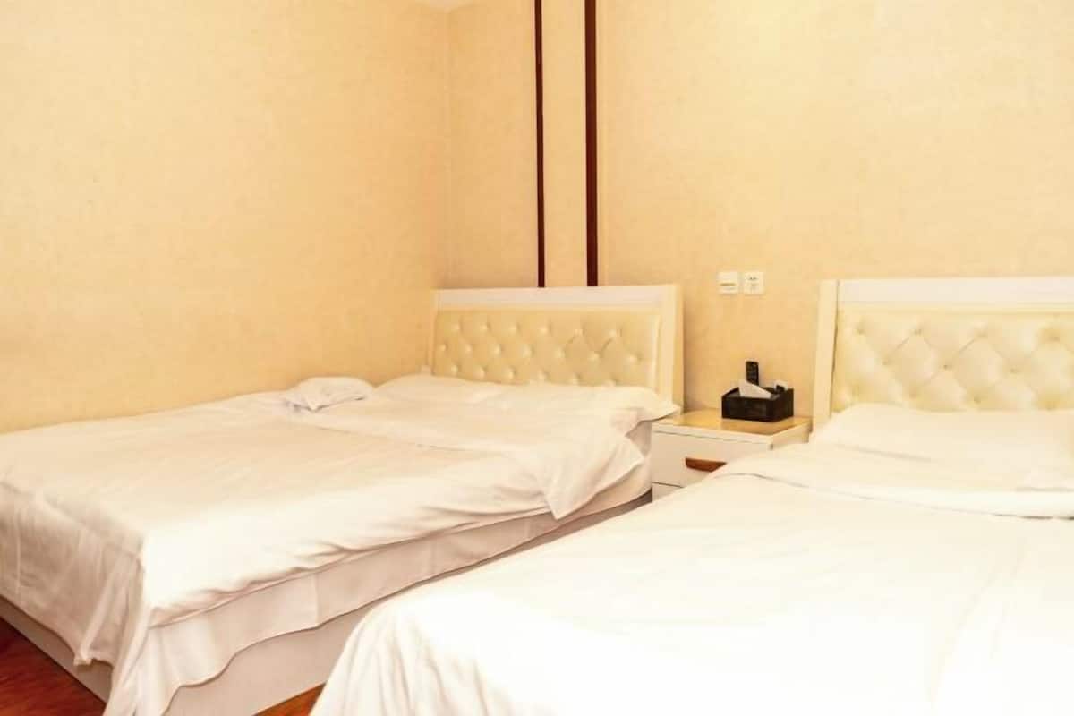 Una habitación de hotel con dos camas, una mesita de noche y un interruptor de luz en la pared.