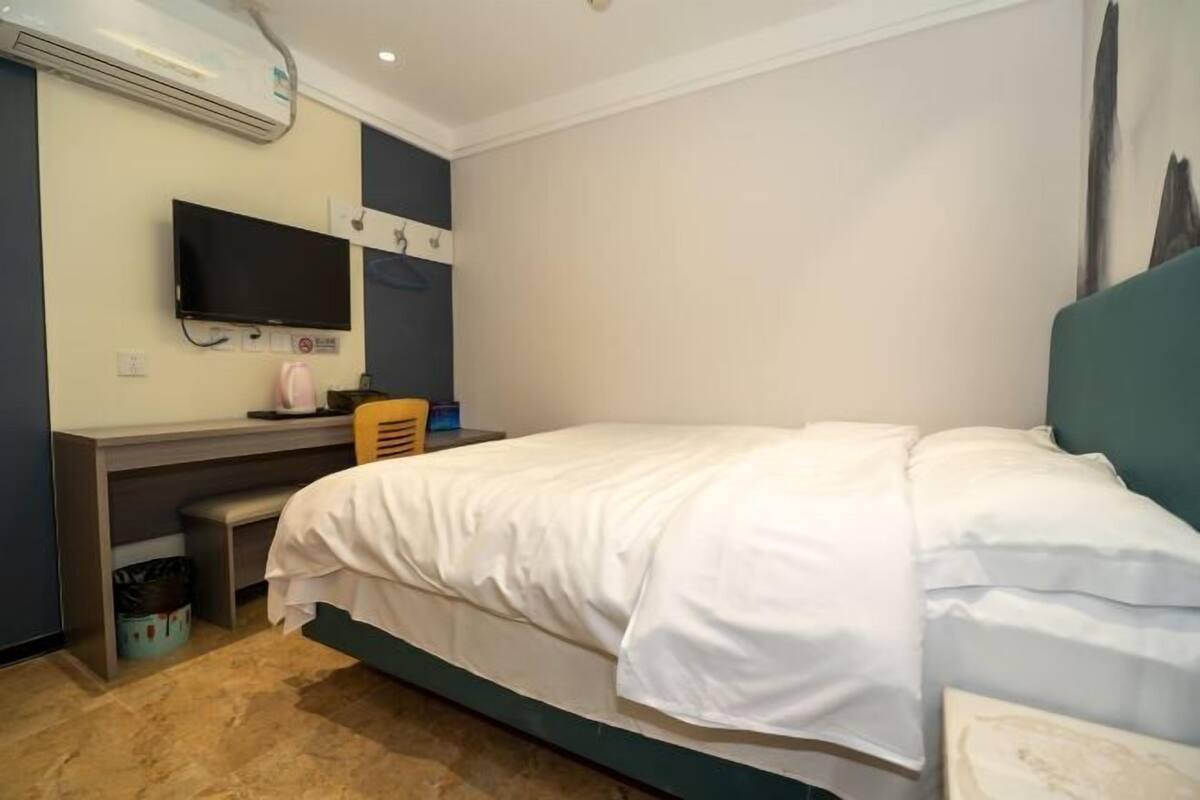 Una habitación de hotel con una cama, un escritorio, un televisor y un aire acondicionado.