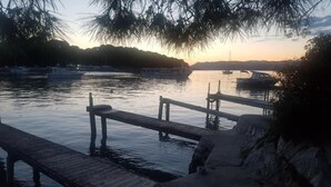 A calm waterfront with wooden docks extending into the water, surrounded by trees and hills in the background. - Apartments Villa Lukas - ''No.3'' Studio Apartment with Balcony and Sea View (Cavtat)